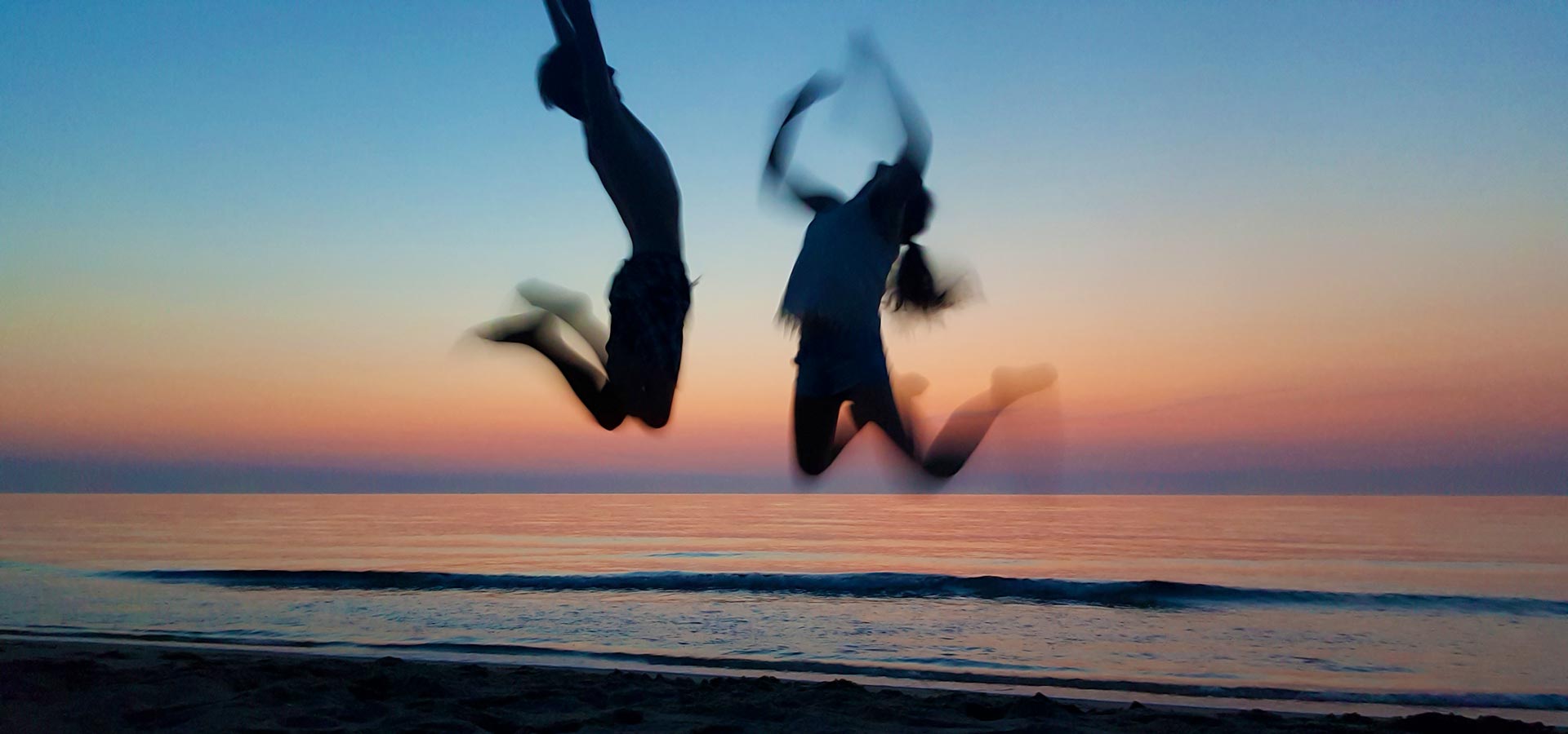 Camping san damiano plage mer mediterranee jeune couple bondissant coucher de soleil